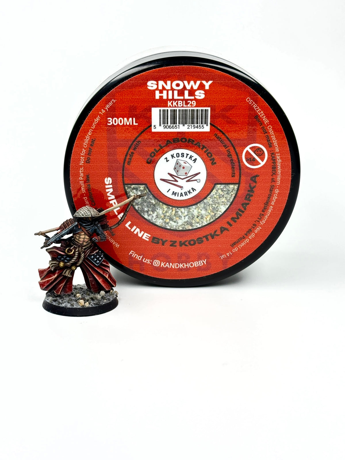 K&K Hobby Snowy Hills Basing-Material 300 ml, Dose von oben mit Sichtfenster, daneben eine bemalte Miniatur